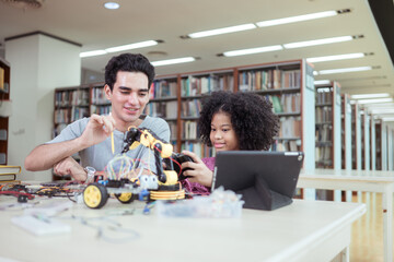 A teacher guiding students in a robotics project during a STEM class in the library