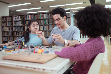 A teacher guiding students in a robotics project during a STEM class in the library