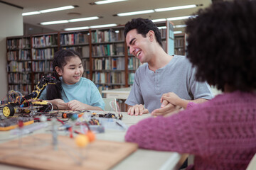 A teacher guiding students in a robotics project during a STEM class in the library