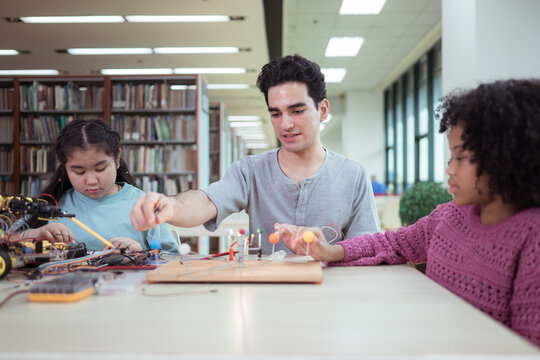 A teacher guiding students in a robotics project during a STEM class in the library - Powered by Adobe