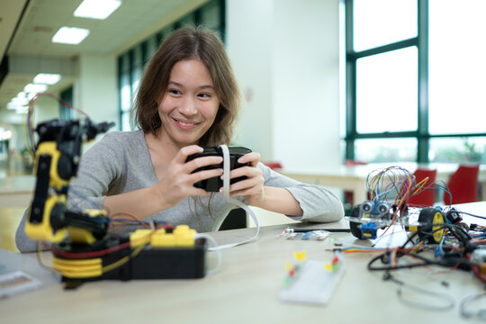A teenage girl student in a robotics project during a STEM class in the library - Powered by Adobe