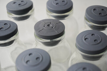 Vials Array Sterile Glass Containers with Gray Caps on White Surface.