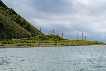 Coastal hillside with utility poles under stormy clouds. Utility poles stretch along a coastal hillside beneath heavy storm clouds. Strait of Tartary, Sea of Japan, Sakhalin Island