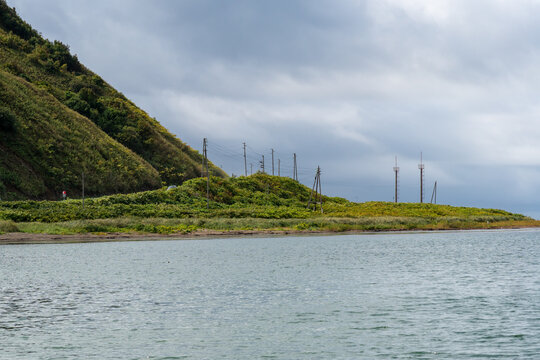 Coastal hillside with utility poles under stormy clouds. Utility poles stretch along a coastal hillside beneath heavy storm clouds. Strait of Tartary, Sea of Japan, Sakhalin Island