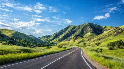 Serene winding road through lush green hills under bright blue sky with fluffy white clouds, perfect for nature lovers and road trip enthusiasts