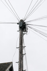 Wooden telephone pole with multiple communication cables and wires against cloudy sky