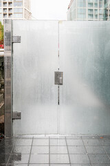 Modern frosted glass gate with raindrops and metal frame in urban city environment