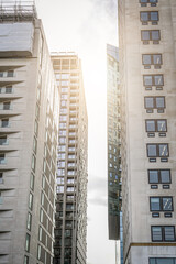 Modern high rise buildings with glass and concrete facades illuminated by sunlight in city center