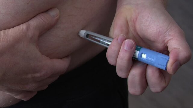 Close up man injects medication into subcutaneous abdomen with drug pen