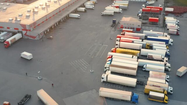 Circular Aerial View: Large Warehouse and Distribution Facility at Dusk | Modern Logistics Center with Trucks at Loading Bays | Industrial Freight Terminal Operations