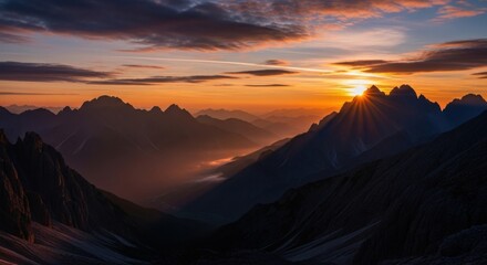 Majestic mountain range silhouette at sunset with vibrant orange sky.