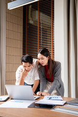 Two asian business persons working together. Businessman brainstorming, having a discussion with her colleague about work project, working on laptop computer at modern office. Business teamwork.