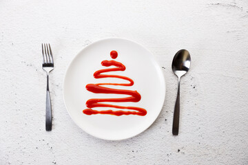 White plate with tomato sauce in Christmas tree shape.