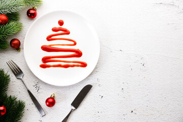 White plate with tomato sauce in Christmas tree shape.