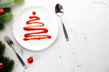White plate with tomato sauce in Christmas tree shape.