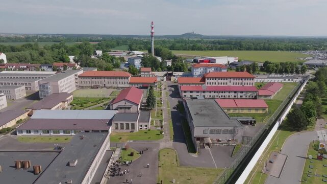 Aerial top-down (nadir) view of prison yards and cell blocks inside perimeter walls; steady overflight, continuous shot, daytime.