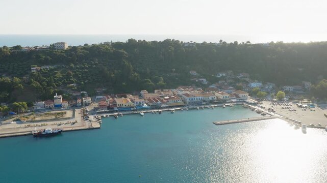 Cinematic panoramic drone shot of Katakolo port with the marina, docks, and waterfront shops under bright Mediterranean sun