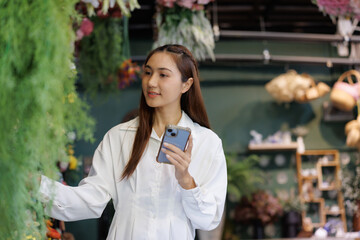 Woman holding smartphone browsing plants in store