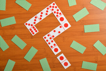 Domino pieces forming a question mark on a wooden table.