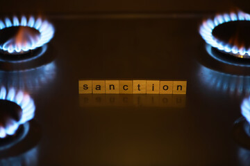 Sanction Concept with Scrabble Letters and Gas Stove Flames in the Background