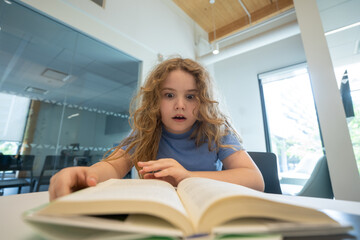 Funny child reading book. Schoolkid studying and reading. Smart kid read book. Little student learning from book. Child reading book in library. Education and Learning. Knowledge through reading.