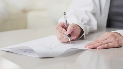 契約書にサインをするアジア人女性の手元