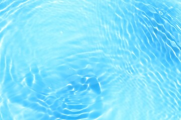 Blue water with ripples on the surface. Defocus blurred transparent blue colored clear calm water surface texture with splashes and bubbles. Water waves with shining pattern texture background.