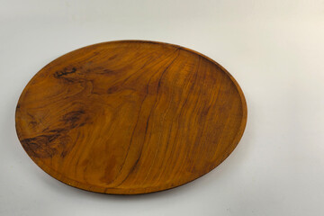 A flat round wooden plate with warm wood grain, placed in the upper left corner of a minimalist white background
