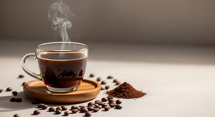 A clear glass mug of steaming hot black coffee on a wooden saucer, surrounded by scattered coffee beans and a pile of ground coffee.