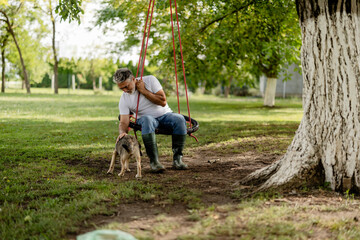 Man petting dog while relaxing on tire swing
