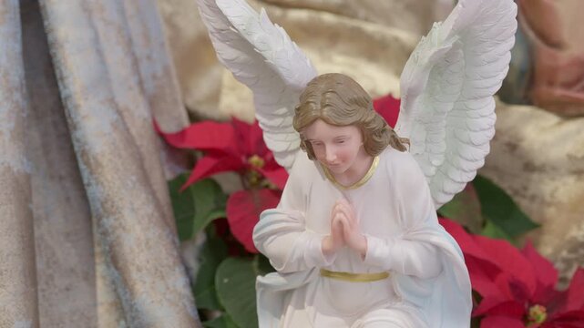 Catholic nativity scene with angels. Christmas religious still life with red flowers prayer and faith detail closeup