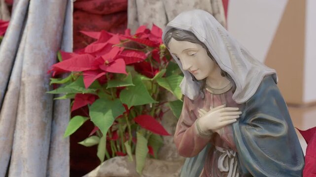 Catholic nativity scene with virgin Mary. Christmas religious still life with red flowers prayer and faith detail closeup