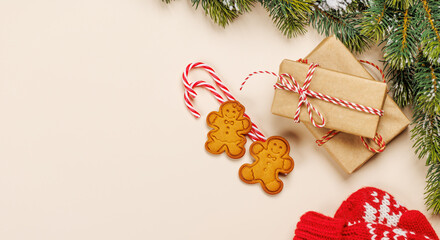 Christmas card with fir branches, gifts and cookies on beige surface