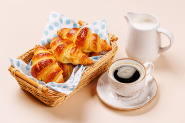 Aromatic croissants in wicker basket with cup of coffee
