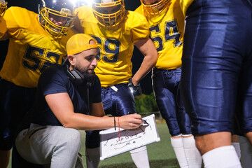 Coach drawing tactics on a whiteboard for players during an American football game