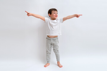 Little child in a white t-shirt pointing with both hands, expressing direction or making a choice. Boy development and education concept. Child aged 4 years (four years old)