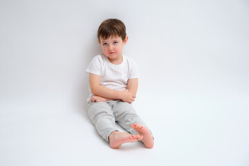 Little kid boy sitting sad and thoughtful on floor with crossed arms. Child feeling unhappy and lonely. Concept of childhood emotions. Child aged 4 years (four years old)