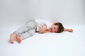 Fototapeta premium Smiling boy lying down on a white background. Happy child resting on a floor. Infant concept for childhood and family health. Child aged 4 years (four years old)