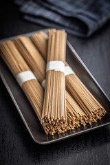 Buckwheat soba noodles on plate on black table.