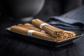 Buckwheat soba noodles on plate on black table.
