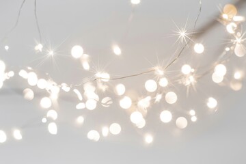 Glowing fairy lights with sparkling starburst effects and soft bokeh against a light background, creating a festive and magical ambiance.