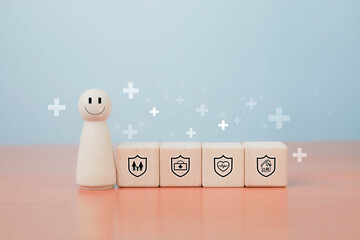 Wooden figure with smile face standing beside cubes with insurance, health, family, and home protection icons on pastel background, symbolizing safety, security, and positive wellbeing.