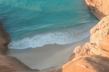 Aerial view of a secluded sandy cove with turquoise ocean water and gentle waves crashing on the shore framed by rugged sun drenched cliffs