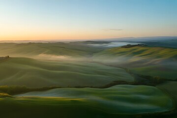 Serene rolling green hills bathed in the soft golden light of sunrise with ethereal mist gently rolling through the valleys creating a dreamlike atmosphere