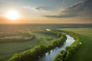 Golden sun setting over a winding river and lush green fields creating a serene and picturesque landscape with dramatic clouds in the sky