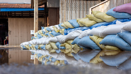 Many sandbags are stacked and reflected in the water.