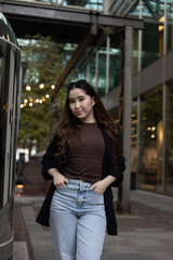 Asian woman in casual-chic outfit under string lights in an urban courtyard — full-length fashion  lifestyle portrait