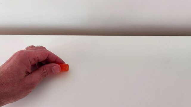 A close-up hand squish delivers pure tactile joy-vibrant orange jelly candy flattens with glossy ripples, soft resistance, and sticky shimmer in a clean, satisfying press