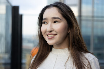 Fototapeta premium Smiling Asian woman with glowing skin and white teeth on a rooftop terrace — fresh, healthy lifestyle portrait for beauty, wellness and dental ads