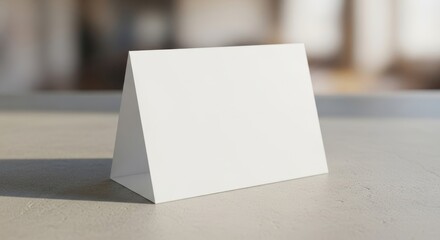 Blank triangular table tent on smooth surface in bright sunlit room